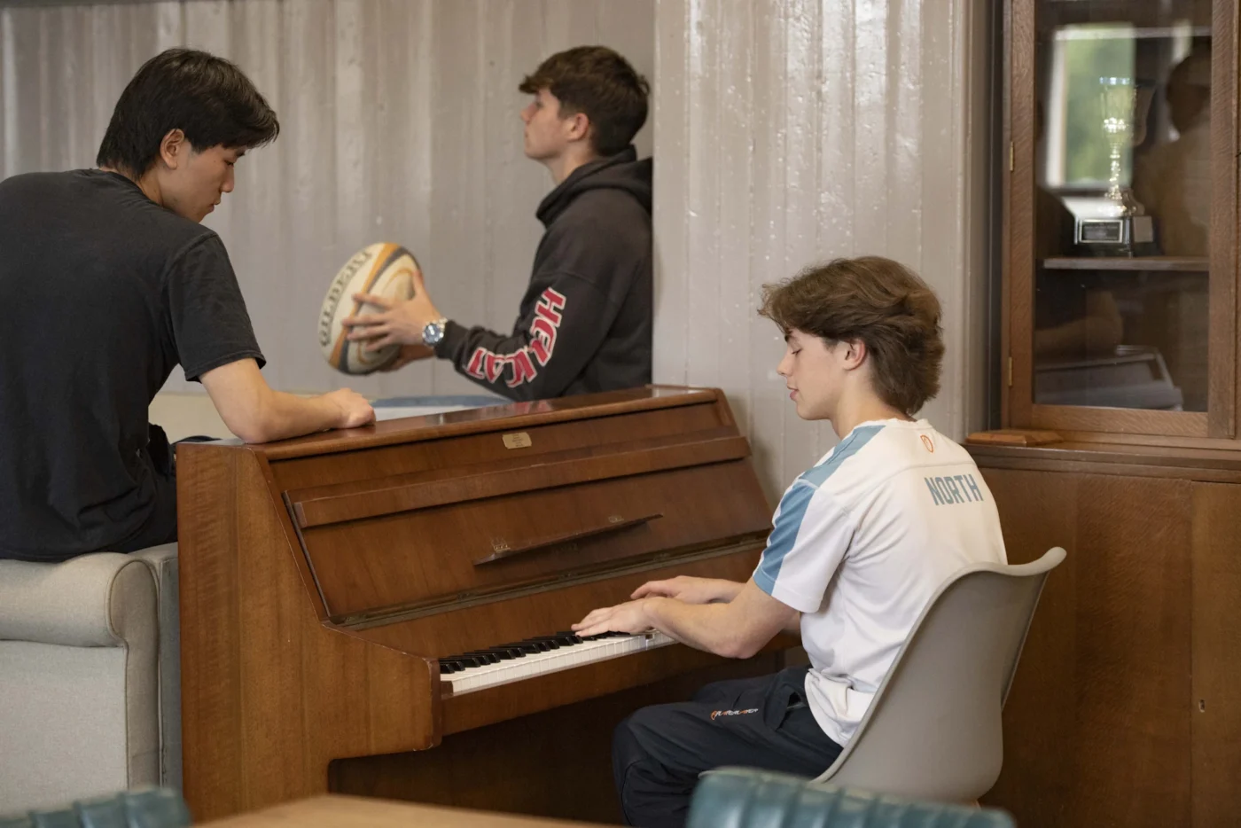 Barnard Castle School boarding pupils playing piano and holding a rugby ball