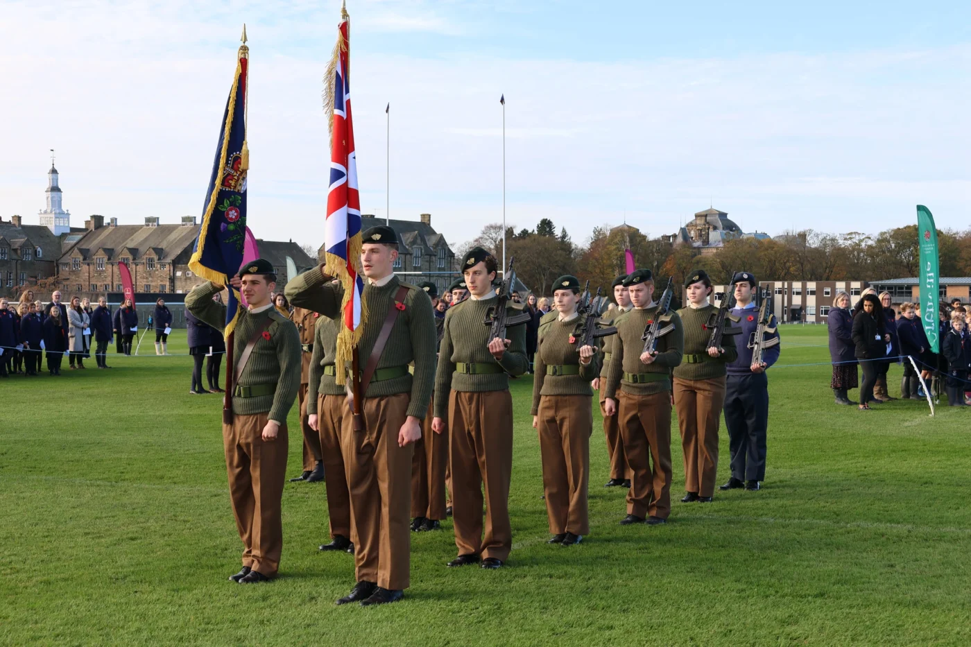Cadets in uniform holding flags on playing field.