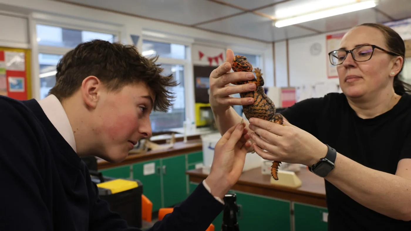 Dawn from Animal Story holds up a lizard for a student to look at.