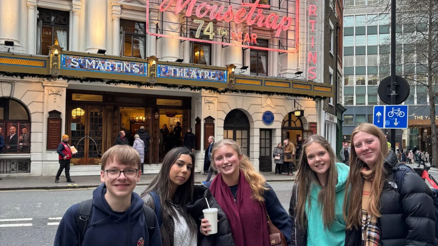 Barney theatre students next to a neon-lit sign for Agatha Christie's The Mousetrap.